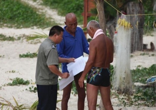 執(zhí)法人員在三亞大東海海灘向游人發(fā)放三亞市政府禁止