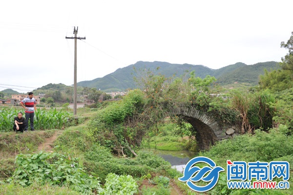 已廢棄的石拱橋,被野草覆蓋,下有溪流,村民稱此路