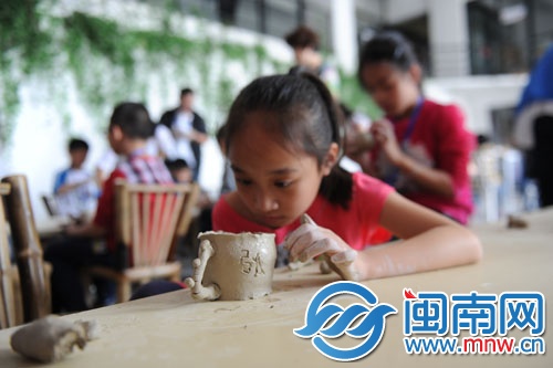 小女孩在陶杯上刻上“張”字